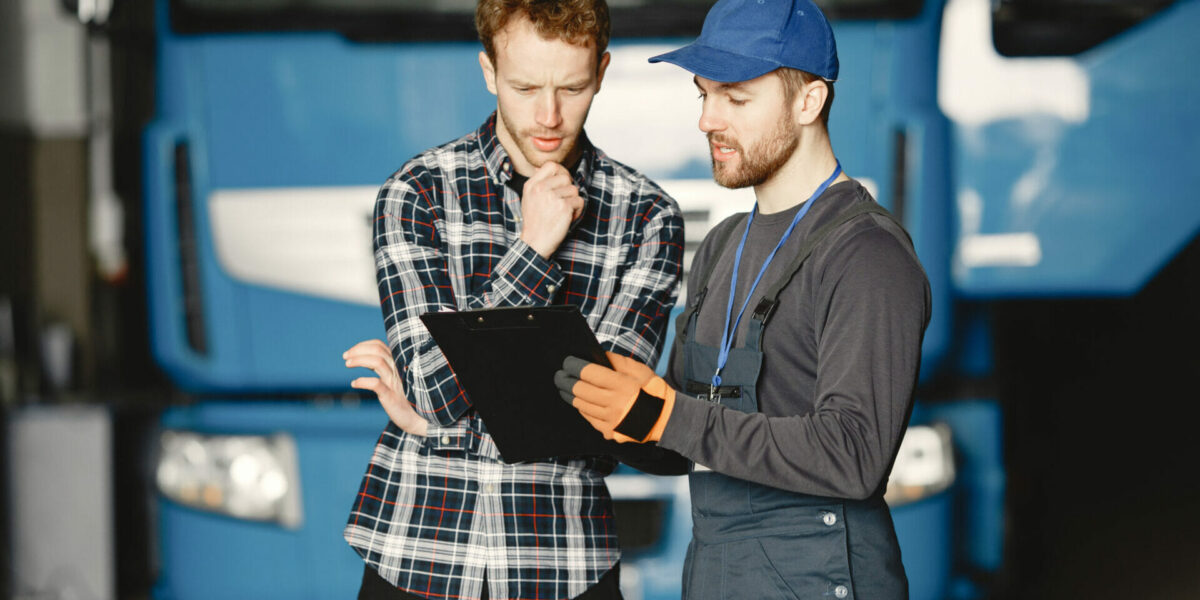 Two guys talking about work. Work in garage near truck. Transfer of documents with goods